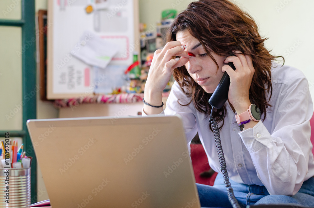 Stressful serious young female employee or student with a laptop talking on the phone grabbing his head in frustration