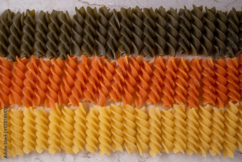 fondo hecho de pasta fusilli de tres colores, seca y cruda en toma cenital photo