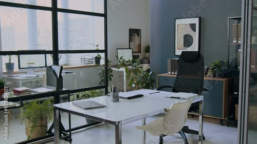 Interior of modern office with minimalist design, white desk, ergonomic chairs, plants and glass wall photo