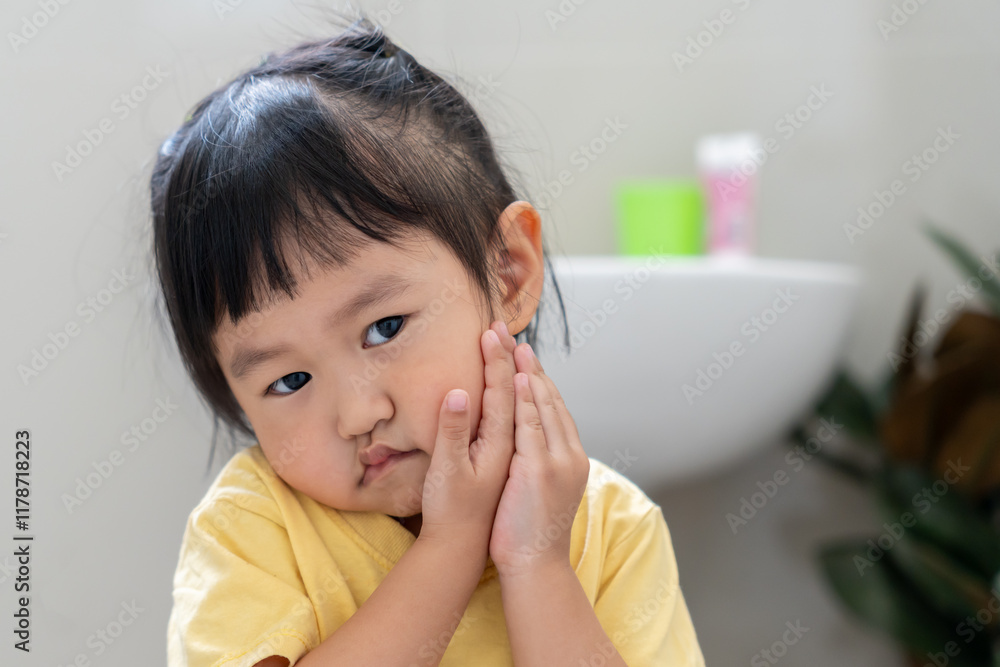 little asian girl presses hand to cheek, suffers from pain in tooth. Teeth decay, dental problems, child emotions and facial expression, oral health care, reducing sweets, fluorine coating little asian girl presses hand to cheek, suffers from pain in tooth. Teeth decay, dental problems, child emotions and facial expression, oral health care, reducing sweets, fluorine coating