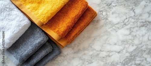 Neatly arranged warm colored hand towels on marble background with empty space for elegant text or design incorporation photo