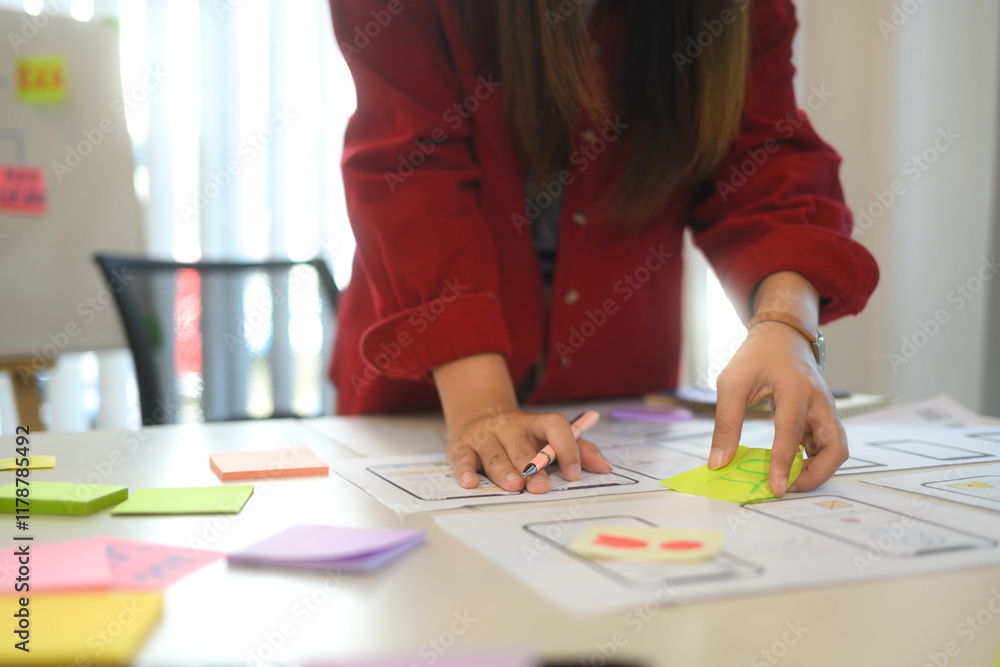Team of creatives collaborating on a UX UI project at workspace filled with flowcharts and digital prototypes Team of creatives collaborating on a UX UI project at workspace filled with flowcharts and digital prototypes