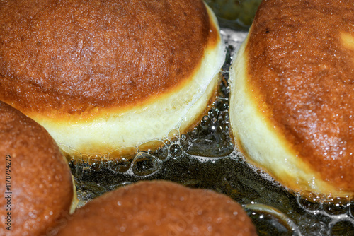 Pączki smażą się na rozgrzanej patelni zanurzone w rozgrzanym tłuszczu z bliska  photo