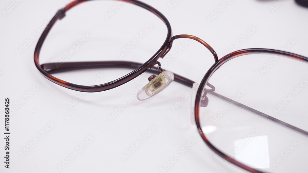 Dirty nose pads on broken eyeglasses. Assortment of broken glasses, broken hinges, missing lenses, cracked or deformed frames. Mix of optical glasses. Workstation for optical technician or optician Dirty nose pads on broken eyeglasses. Assortment of broken glasses, broken hinges, missing lenses, cracked or deformed frames. Mix of optical glasses. Workstation for optical technician or optician