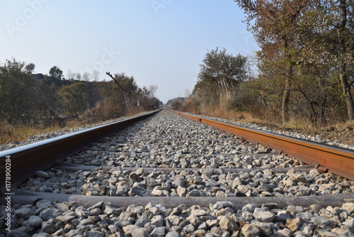 Here A single-track railway line captured symmetrically, offering a calm, ordered perspective into the horizon. This minimalist scene emphasizes clarity, direction, Pair of empty train tracks
