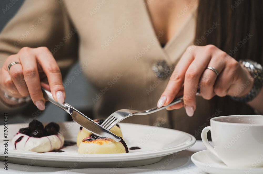 A close-up of a person elegantly cutting into a delicious dessert on a plate, featuring berries and cream, with a cup of coffee nearby, highlighting a delightful dining experience. A close-up of a person elegantly cutting into a delicious dessert on a plate, featuring berries and cream, with a cup of coffee nearby, highlighting a delightful dining experience.