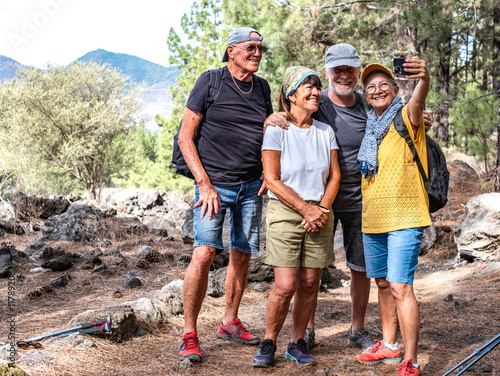 Happy group of senior friends enjoying retirement and adventure trekking in the forest, four elderly people take a selfie smiling. Sport, freedom, healthy lifestyle concept #1178920821