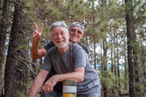 Happy couple of senior active men friends enjoying vacation and adventure trekking in the forest, two smiling elderly males. Sport, freedom, healthy lifestyle concept #1178920887