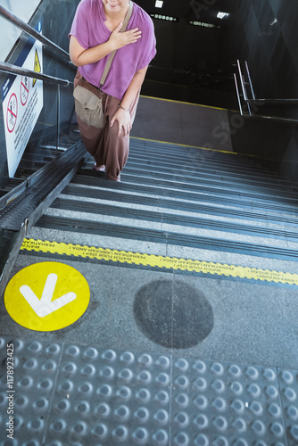 Fotografie Asian adult woman with sling bag climbing up the subway station steep stairs wit