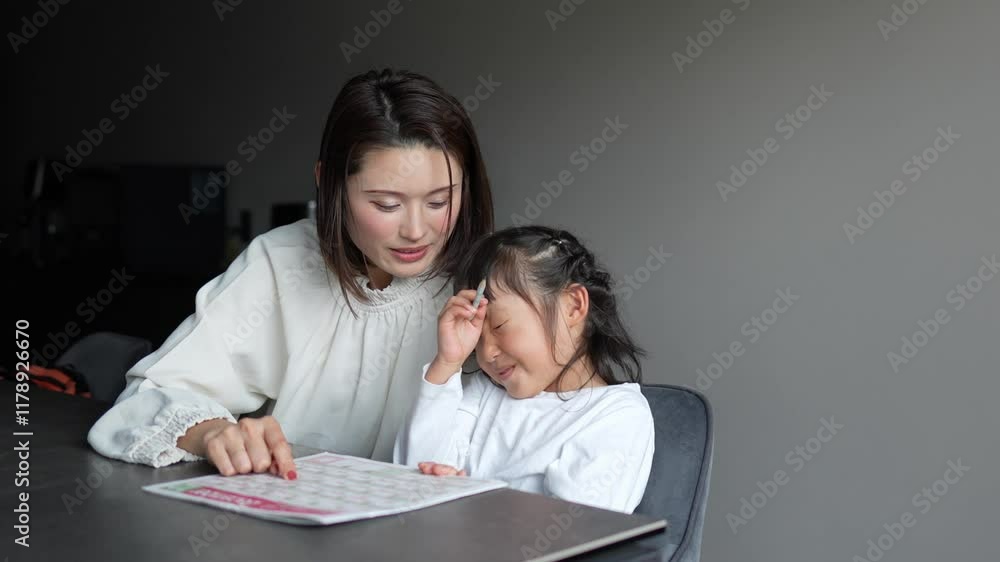 A Japanese parent and child, a woman in her 30s, a man in his 20s, and a 6-year-old girl, wearing simple white clothes, are studying English in their living room. A Japanese parent and child, a woman in her 30s, a man in his 20s, and a 6-year-old girl, wearing simple white clothes, are studying English in their living room.