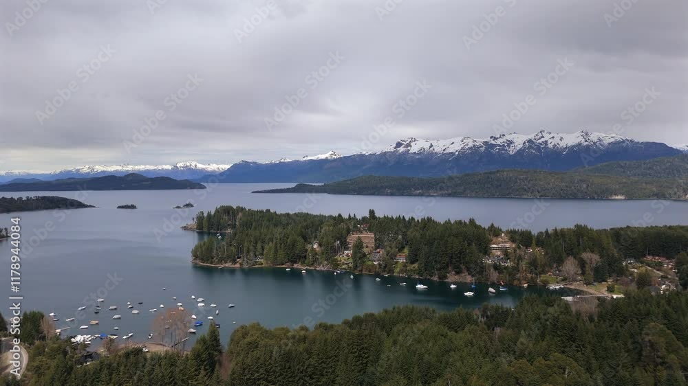 Stunning aerial view of Puerto Manzano in Villa La Angostura, Neuquén, Argentina, with anchored boats and the majestic Lake Nahuel Huapi as backdrop, surrounded by snow-capped mountains. Stunning aerial view of Puerto Manzano in Villa La Angostura, Neuquén, Argentina, with anchored boats and the majestic Lake Nahuel Huapi as backdrop, surrounded by snow-capped mountains.