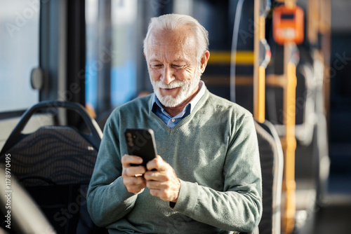 Smart causal senior passenger sitting in a public transportation and typing on his phone.