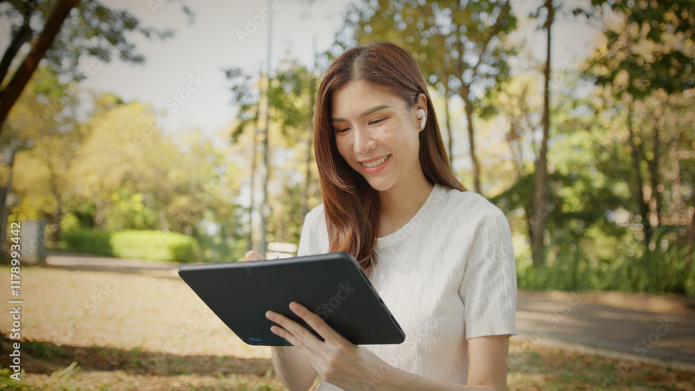 Asian Woman Working outdoors in the park. Professional on a Video Call, exploring Hybrid Work Opportunities in a Peaceful, Virtual Meeting and Online Learning. Hybrid work lifestyle concept by tablet Asian Woman Working outdoors in the park. Professional on a Video Call, exploring Hybrid Work Opportunities in a Peaceful, Virtual Meeting and Online Learning. Hybrid work lifestyle concept by tablet