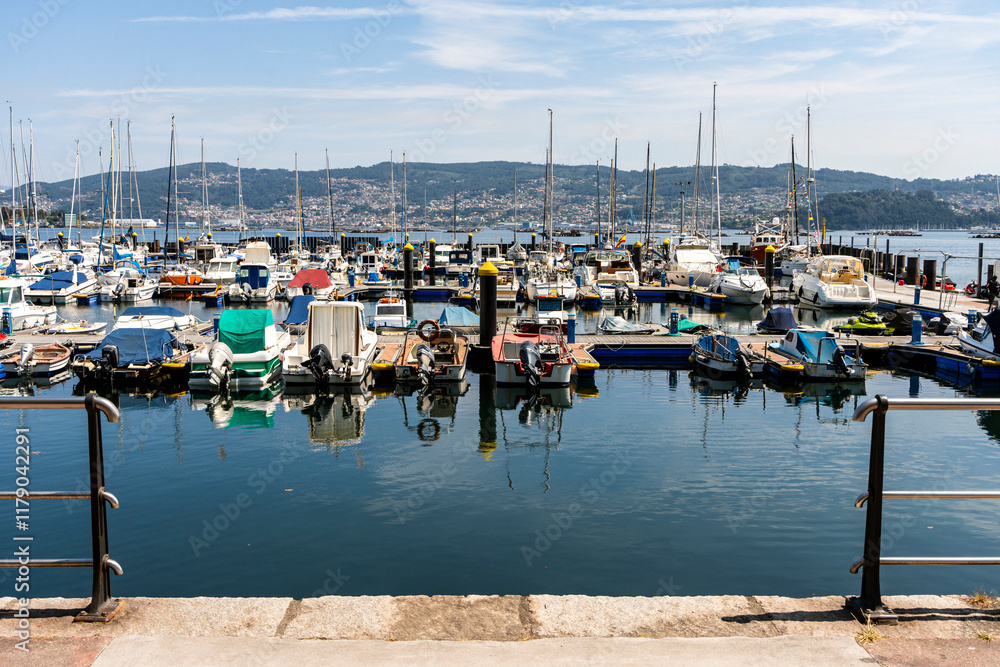 Boats by the coast on Marina of Moana with residential houses in the background, Galicia, Spain