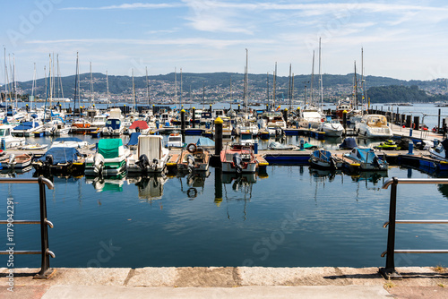 Obraz na płótnie Boats by the coast on Marina of Moana with residential houses in the background, Galicia, Spain w salonie