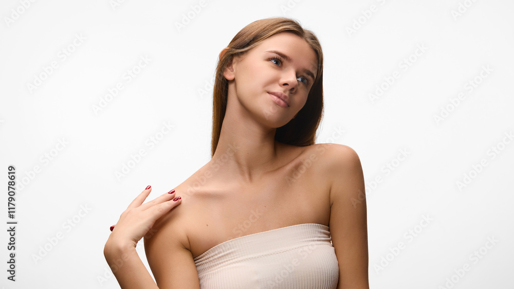 Obraz premium Portrait of young beautiful girl posing against white studio background. Female model in black top show her flowerless skin. Concept of natural beauty, self care, dermatology. Ad