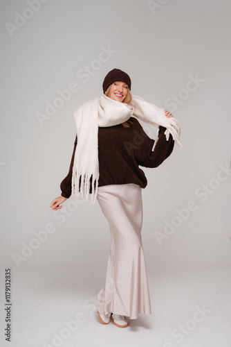 Trendy woman in stylish spring,autumn outfit smiling to the camera while posing on studio background.