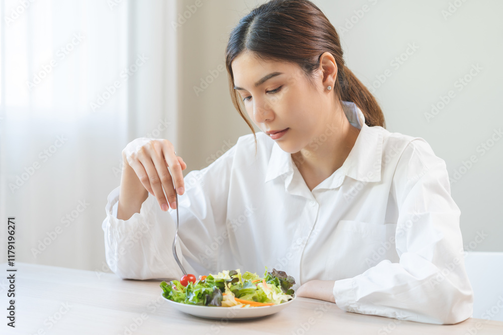 Diet in bored face, unhappy beautiful asian young woman, girl on dieting, holding fork at tomato on salad plate, dislike or tired with eat fresh vegetables. Nutrition of clean, healthy food good taste Diet in bored face, unhappy beautiful asian young woman, girl on dieting, holding fork at tomato on salad plate, dislike or tired with eat fresh vegetables. Nutrition of clean, healthy food good taste