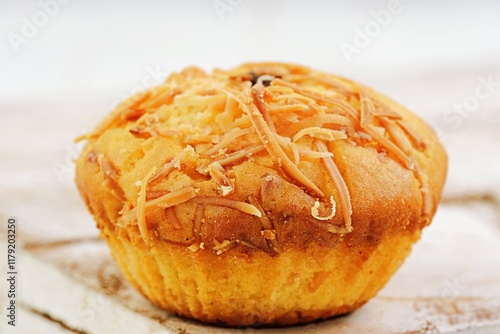 Delicious homemade cheese muffin topped with grated cheddar and a sweet raisin, baked to perfection. A soft, golden-brown treat perfect for breakfast, snacks, or desserts, showcasing classic flavors photo