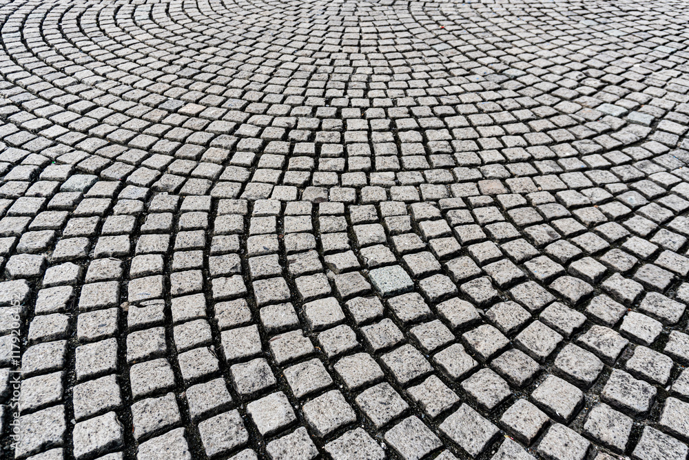 Fototapeta premium A circular pattern of gray cobblestones laid out in an arc, creating a textured, repeating design.