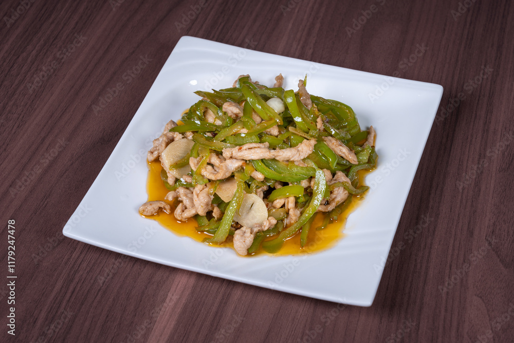 Shredded pork with green pepper on a white plate on the table Shredded pork with green pepper on a white plate on the table