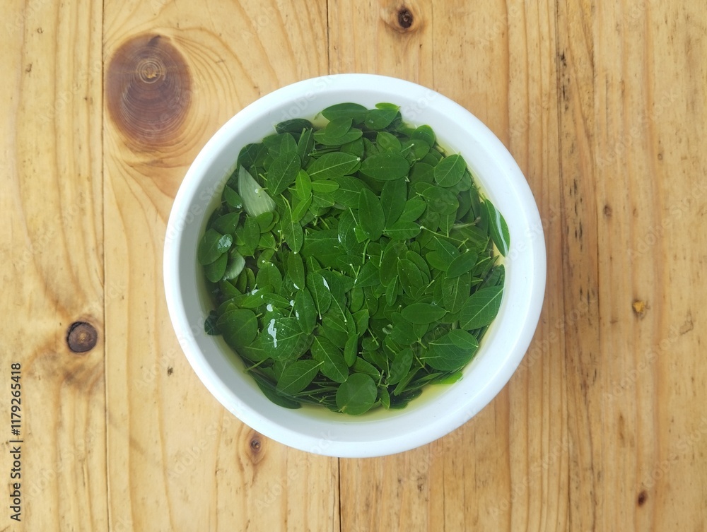 Moringa leaves soup in bowl on wooden table Top view angle setup Moringa leaves soup in bowl on wooden table Top view angle setup