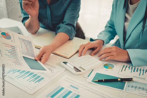 Two Asian women are reviewing financial transaction documents and calculating expenses with a business idea calculator to increase profits and business strength. photo