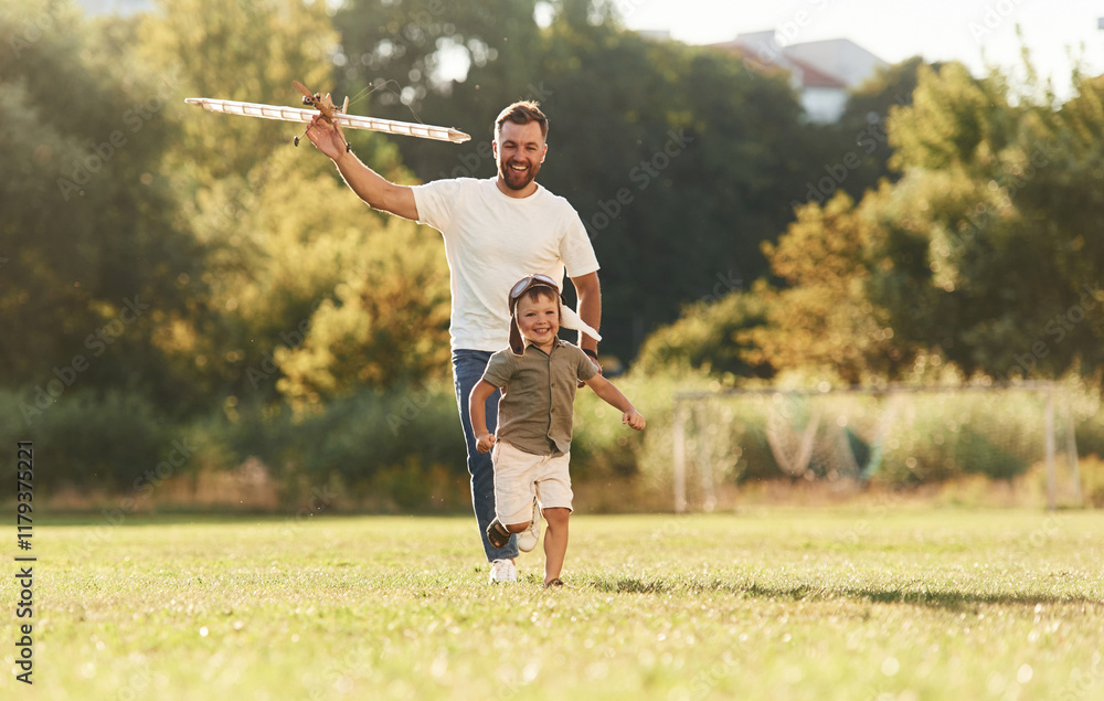 Fototapeta premium Active weekend, running. Father and son are on the field together with toy plane