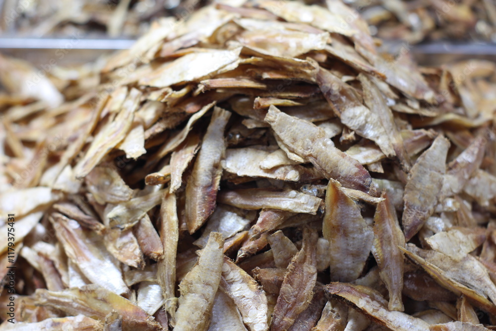 Crispy small fish placed on the stall for sale. Close up of stacked dried anchovies. A pile of dried anchovies displayed in a fish market, Little dried fish in an Asian fish market. Crispy small fish placed on the stall for sale. Close up of stacked dried anchovies. A pile of dried anchovies displayed in a fish market, Little dried fish in an Asian fish market.