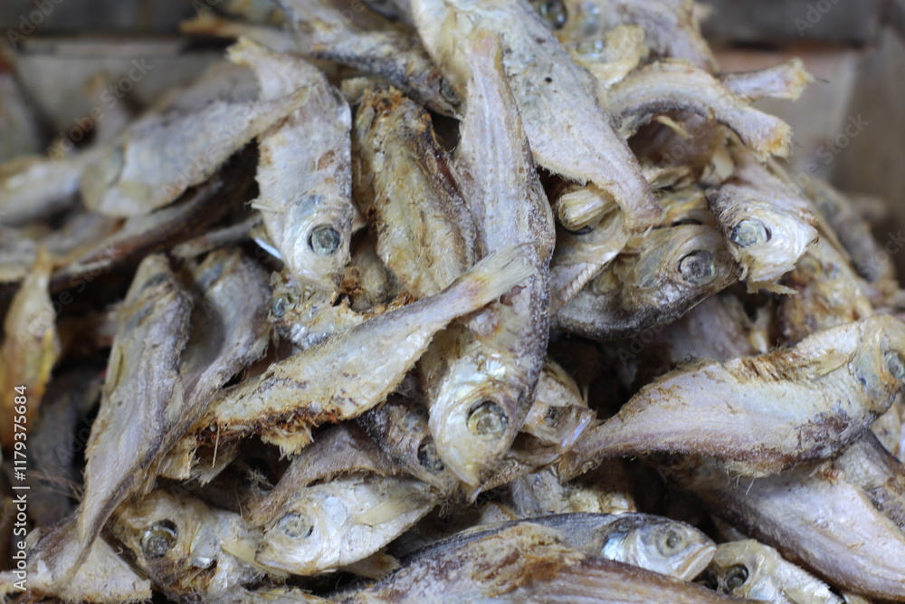 Crispy small fish placed on the stall for sale. Close up of stacked dried anchovies. A pile of dried anchovies displayed in a fish market, Little dried fish in an Asian fish market. Crispy small fish placed on the stall for sale. Close up of stacked dried anchovies. A pile of dried anchovies displayed in a fish market, Little dried fish in an Asian fish market.