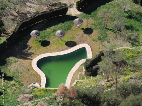 Fantastischer Blick von Oben auf ein grünes Schwimmbecken mit Palmensonnenschirmen in Ronda Spanien photo