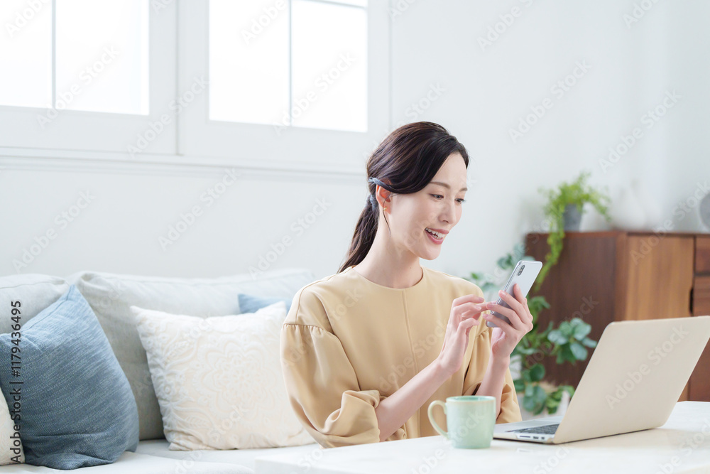 家でパソコンとスマホで仕事する女性 家でパソコンとスマホで仕事する女性
