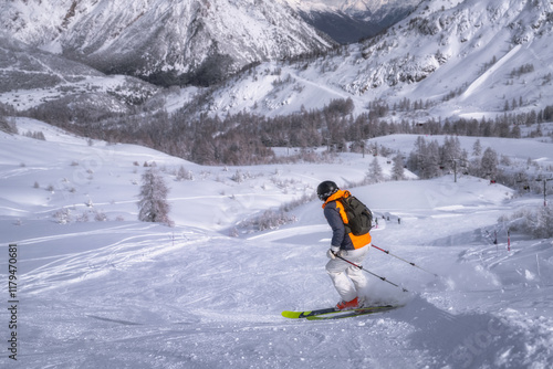 A highly skilled skier gracefully glides down a breathtaking snowy slope, surrounded by stunning mountain views, crafting a picturesque winter wonderland, Montgenevre ski village, Alps, France photo