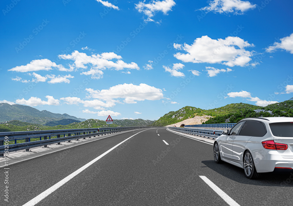 The car is driving along the highway surrounded by picturesque nature.