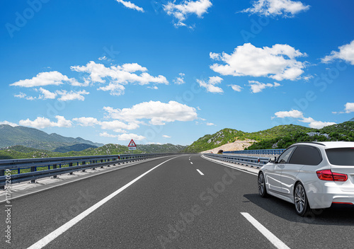 The car is driving along the highway surrounded by picturesque nature.