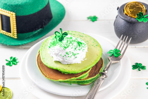 Green shamrock color pancakes with whipped cream and sugar sprinkles, for St Patrick`s day breakfast on lunch, with patricks holiday decorations on kitchen table photo