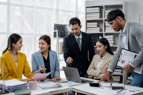 A group of people are gathered around a laptop, discussing something