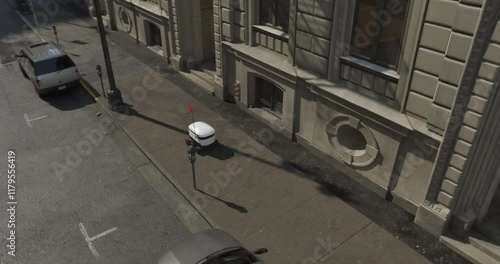 An autonomous delivery robot navigates a city sidewalk. Equipped with a flagpole for visibility, it moves efficiently past parked cars and urban infrastructure, showcasing modern mobility solutions