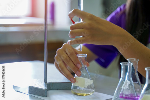 Close-up of a student performing an acid-base titration experiment. Concept of chemistry lab, science, experiment, skills, learning.