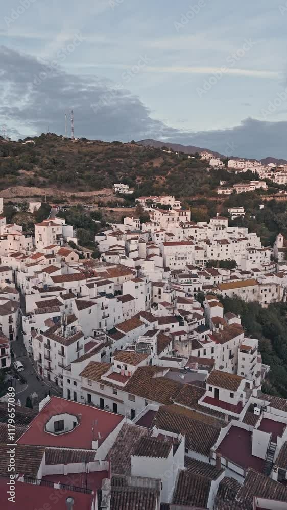 Serene view of a white village and hillside at sunset with contemplative silhouette Serene view of a white village and hillside at sunset with contemplative silhouette