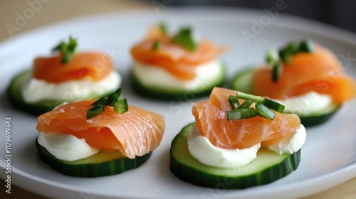 Appetizing cucumber canapÃ©s topped with smoked salmon and cream cheese garnished with fresh chives on a white plate photo