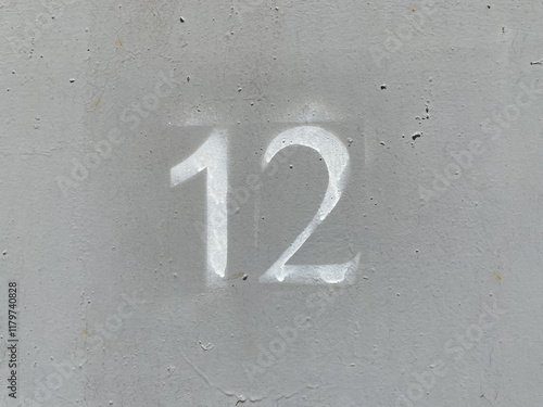 White number 12 on aged background. Twelve on textured gray surface photo