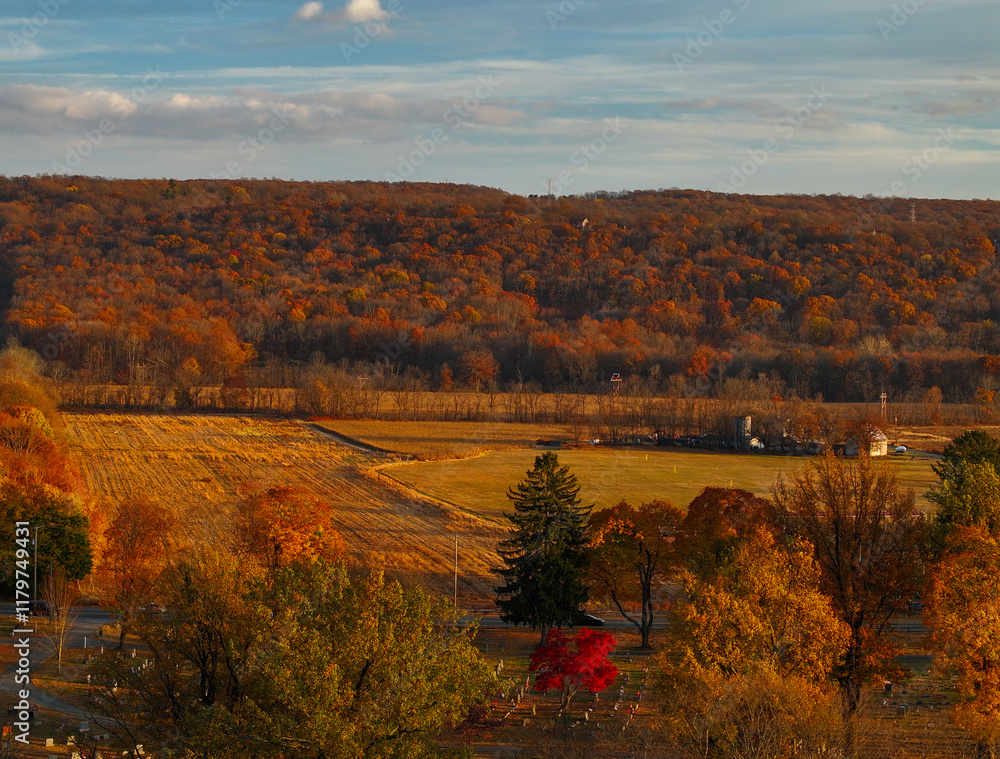 Obraz premium A rural farmland next to graveyard and mountains in autumn