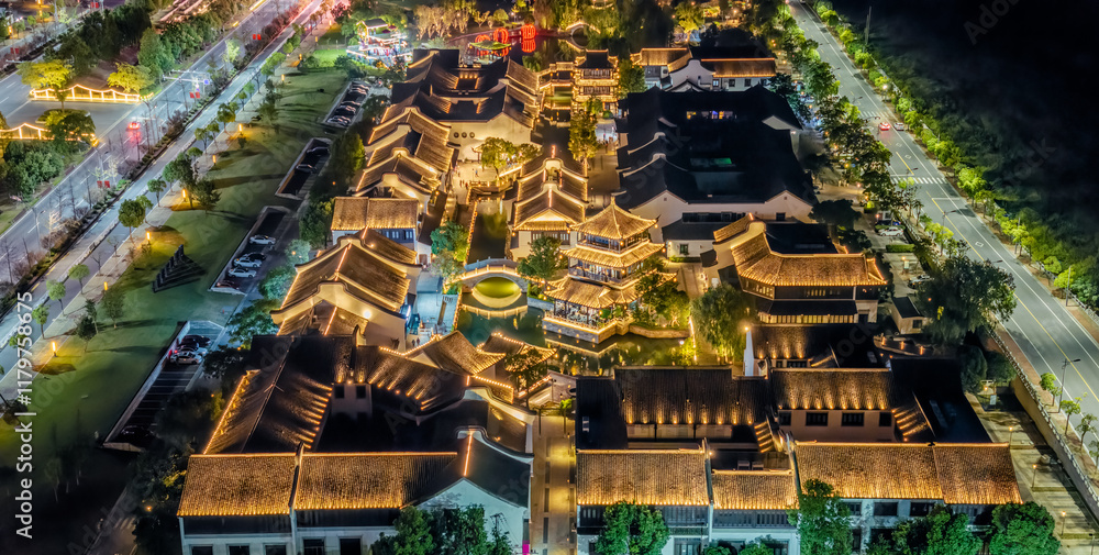 Aerial view of ancient Chinese architecture with traditional rooftops and illuminated buildings in an oriental style city at night.