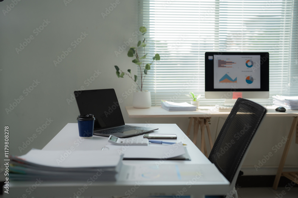Well-organized office desk displaying financial charts on a computer, accompanied by a laptop, calculator, and smartphone, fosters a productive business environment Well-organized office desk displaying financial charts on a computer, accompanied by a laptop, calculator, and smartphone, fosters a productive business environment