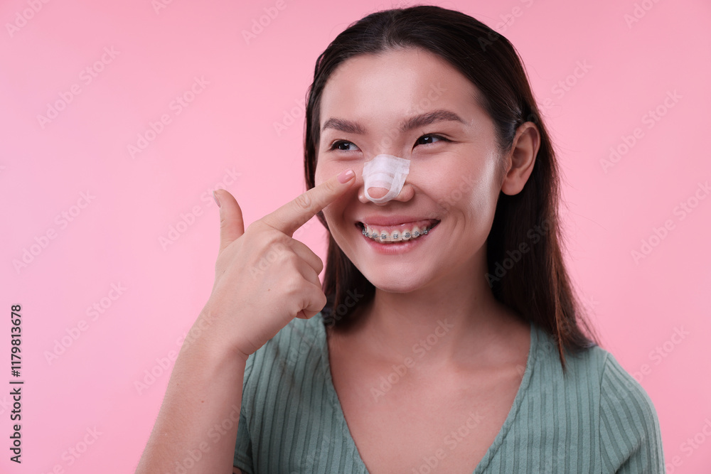 Woman with medical bandage on her nose after plastic surgery operation against pink background Woman with medical bandage on her nose after plastic surgery operation against pink background