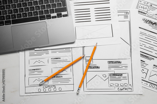 Developing UI design. Sketches of website wireframes, laptop and pencils on white marble table, top view photo