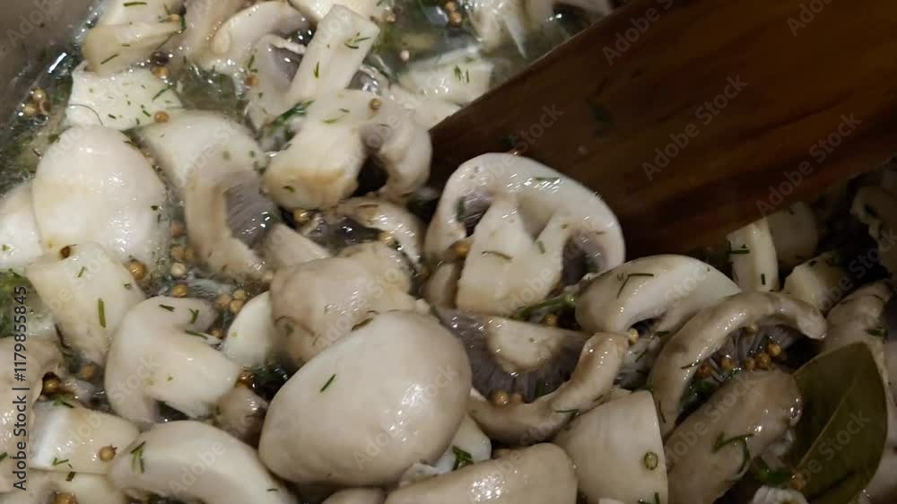 Close-up of chef with wooden spatula interferes with chopped champignon mushrooms in pan Close-up of chef with wooden spatula interferes with chopped champignon mushrooms in pan