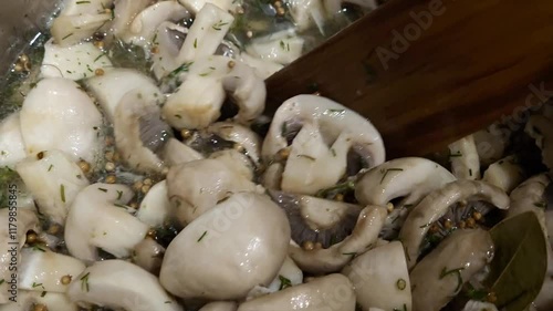 Close-up of chef with wooden spatula interferes with chopped champignon mushrooms in pan photo