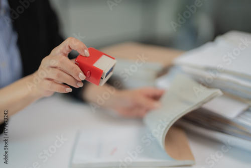 Obraz na plátně Female hands holding an automatic stamp while browsing through documents, managi